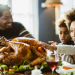 A joyful family with a young child reaches for a roasted turkey on a festive table during a holiday meal, expressing excitement and happiness.