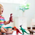 A joyful young child playing with colorful dinosaur toys in a bright, airy room, laughing gleefully while sitting on the floor.