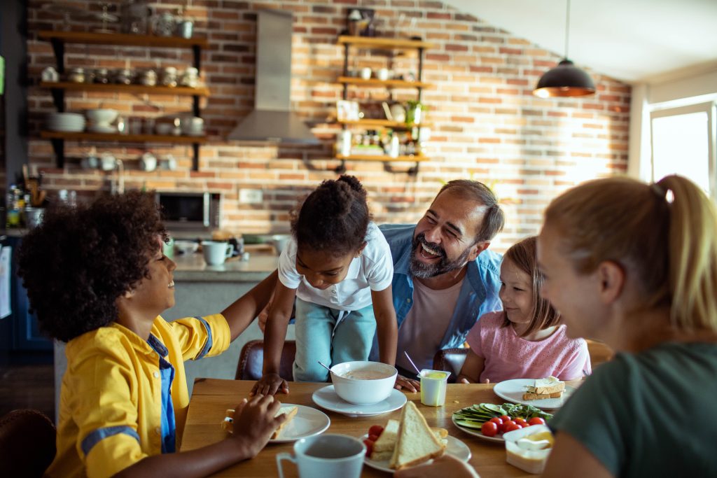 Multiracial family laughing and sharing a meal at a table